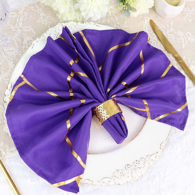 Purple napkin with gold stripes styled elegantly on a decorative plate.