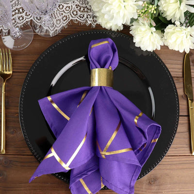 Purple napkin with gold accents elegantly arranged on a black plate.