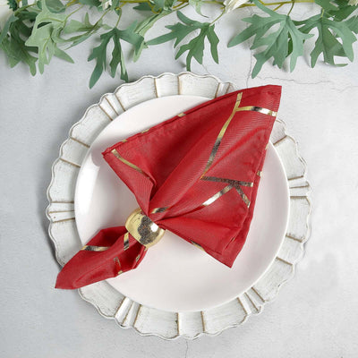 Red napkin with gold accents elegantly tied on a decorative plate.