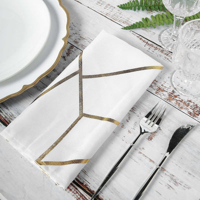 Elegant white napkin with gold geometric design on rustic table setting.