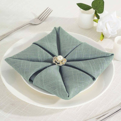 Elegant teal napkin with decorative pearl brooch on a white plate.