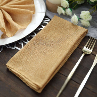 Rustic brown linen napkin on a wooden table with cutlery and flowers.