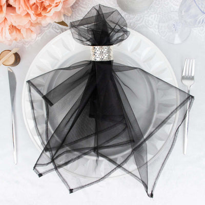 Elegant black tulle napkin with rhinestone ring on a white plate.