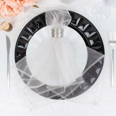 Elegant table setting with a black plate and sheer white napkin decoration.