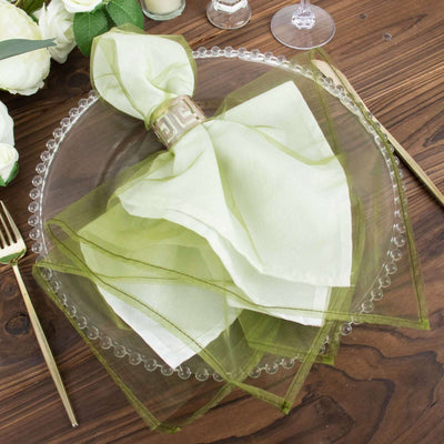Green organza napkin with gold ring on a decorative plate.