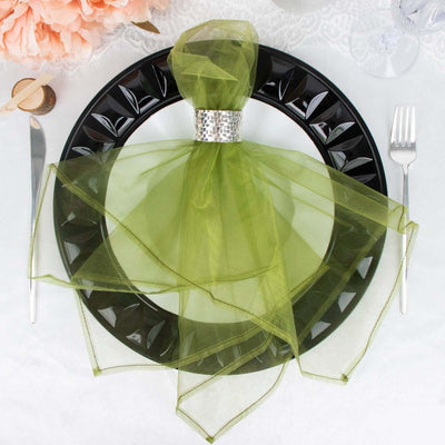 Green organza table napkin tied with a silver ring on a black plate.