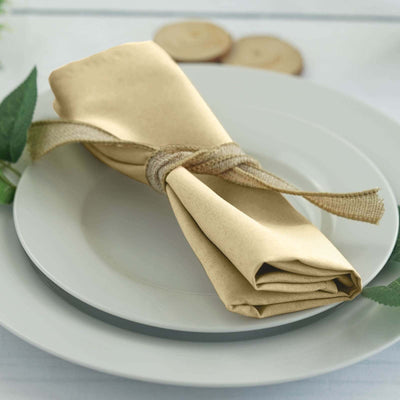 Gold napkin tied with burlap on a white plate, elegantly arranged for dining.