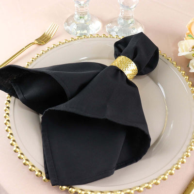 Elegant black napkin with gold ring on a decorative plate.
