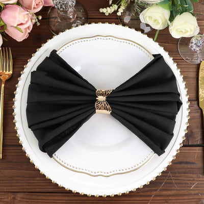 Black napkin elegantly folded into a bow on a decorative plate.
