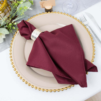 Burgundy napkin elegantly folded on a decorative plate setting.