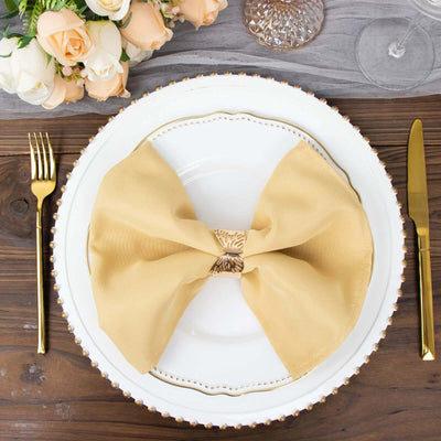 Elegant gold napkin bow on a decorative plate at a dinner setting.