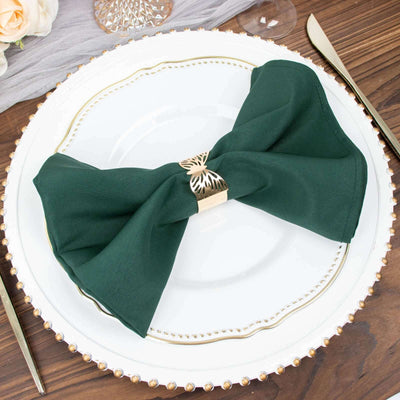 Elegant green napkin with gold ring on a decorative plate.
