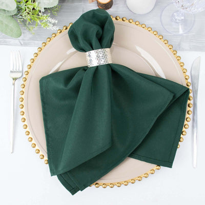 Green napkin elegantly arranged on a plate with a silver napkin ring.