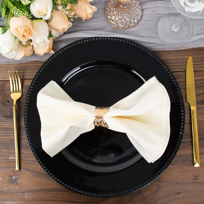 Elegant cream napkin bow on a black plate, set for a sophisticated dining experience.