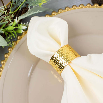 Elegant cream napkin with gold ring on a decorative plate.