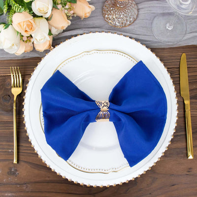 Elegant blue bow napkin on a white plate with gold trim, set for dining.