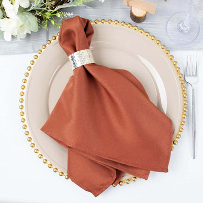Brown napkin with silver ring on a decorative plate setting.