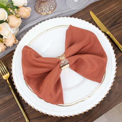 Rustic terracotta napkin elegantly styled on a decorative plate with gold accents.