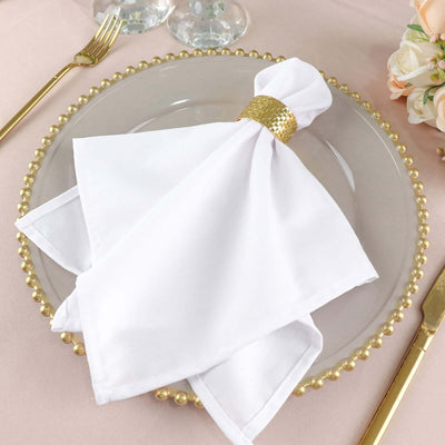 Elegant white napkin with gold ring on a decorative plate.