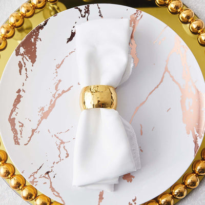 Elegant white napkin with gold ring on a decorative marble plate.