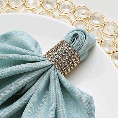 Elegant blue napkin with jeweled ring on a white plate.