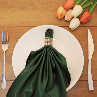 Elegant green napkin on a white plate, styled with silver ring and tulips.