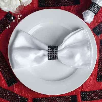 Elegant white satin bow tie on a plate, adorned with black rhinestone band.