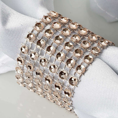 Rose gold crystal napkin ring on white fabric backdrop.