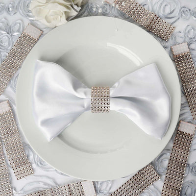 Elegant white satin bow with crystal embellishment on a plate.