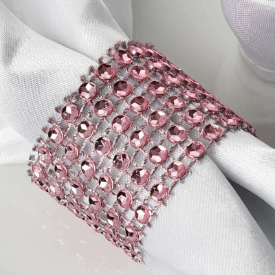 Pink rhinestone napkin ring on white fabric.