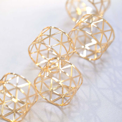 Gold geometric rings arranged artistically on a soft surface.