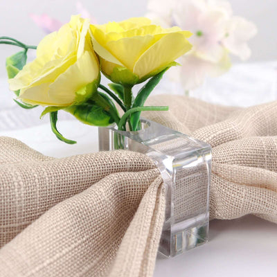 Clear acrylic flower holder with yellow roses and beige fabric.