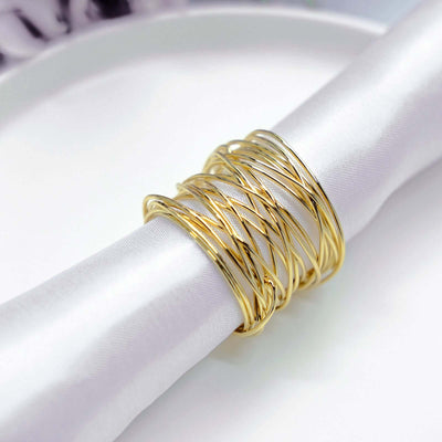 Gold twisted bangles on a white napkin.