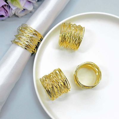 Gold wire napkin rings on a white plate with a satin napkin.