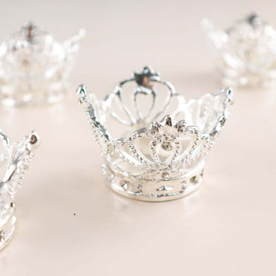 Silver crown-shaped candle holders on a light background.