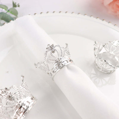 Silver crown napkin rings on a white plate.