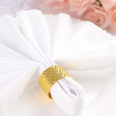 Gold woven napkin ring on white napkin, elegantly styled for dining.