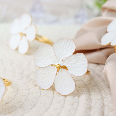 White flower hairpin with gold accents on a textured surface.