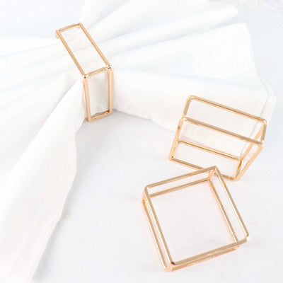Gold metal napkin rings on a white fabric backdrop.