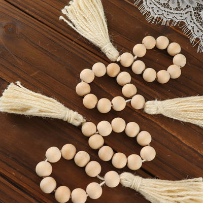 Natural wooden bead garland with tassels on a rustic wooden surface.
