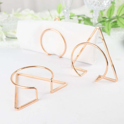 Rose gold napkin holders in geometric shapes on a table setting.