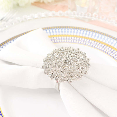 Elegant crystal napkin ring atop a white napkin on a decorative plate.