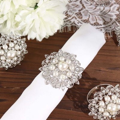 Elegant silver and pearl napkin rings on a white napkin, adorned with floral decor.