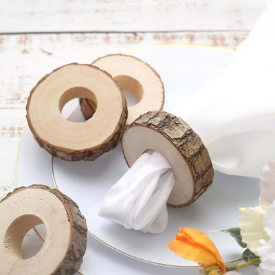 Natural wood napkin rings on a white plate with floral accents.