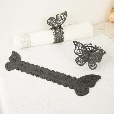 Black lace butterfly napkin rings and holder on a white tablecloth.
