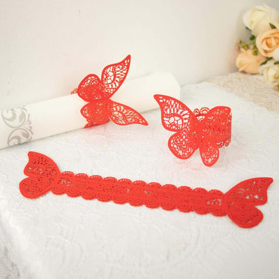 Red lace butterfly-themed table decor pieces on white lace background.