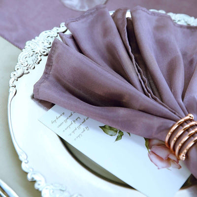 Elegant mauve napkin draped on a silver platter with a floral card.