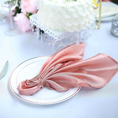 Elegant pink satin napkin arranged on a white plate at a beautifully set table.