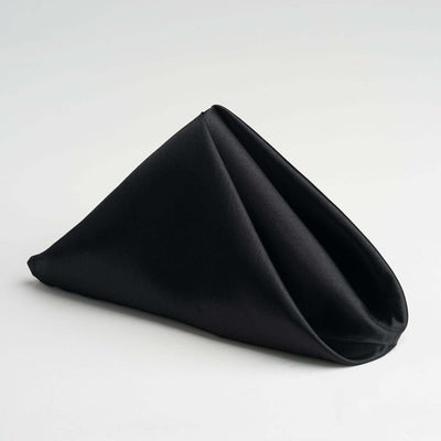 Black fabric napkin elegantly folded in a triangular shape.