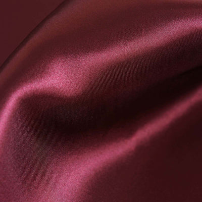 Burgundy satin fabric texture close-up shot.